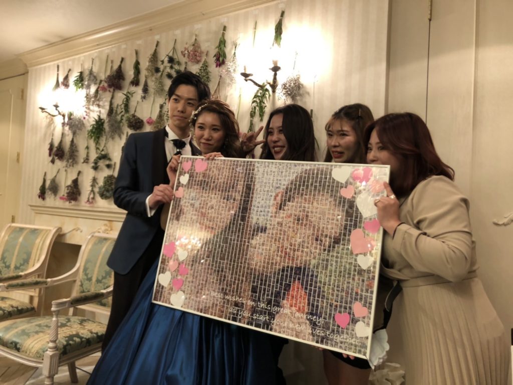 結婚式でモザイクアートポスターを持つ新郎新婦とゲスト